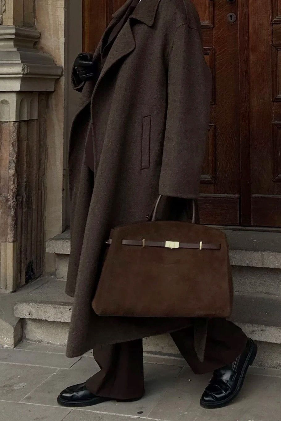Brązowy rozkloszowany płaszcz z paskiem  w stylizacji z czekoladowym eleganckim komplecie garniturowym - widok z boku