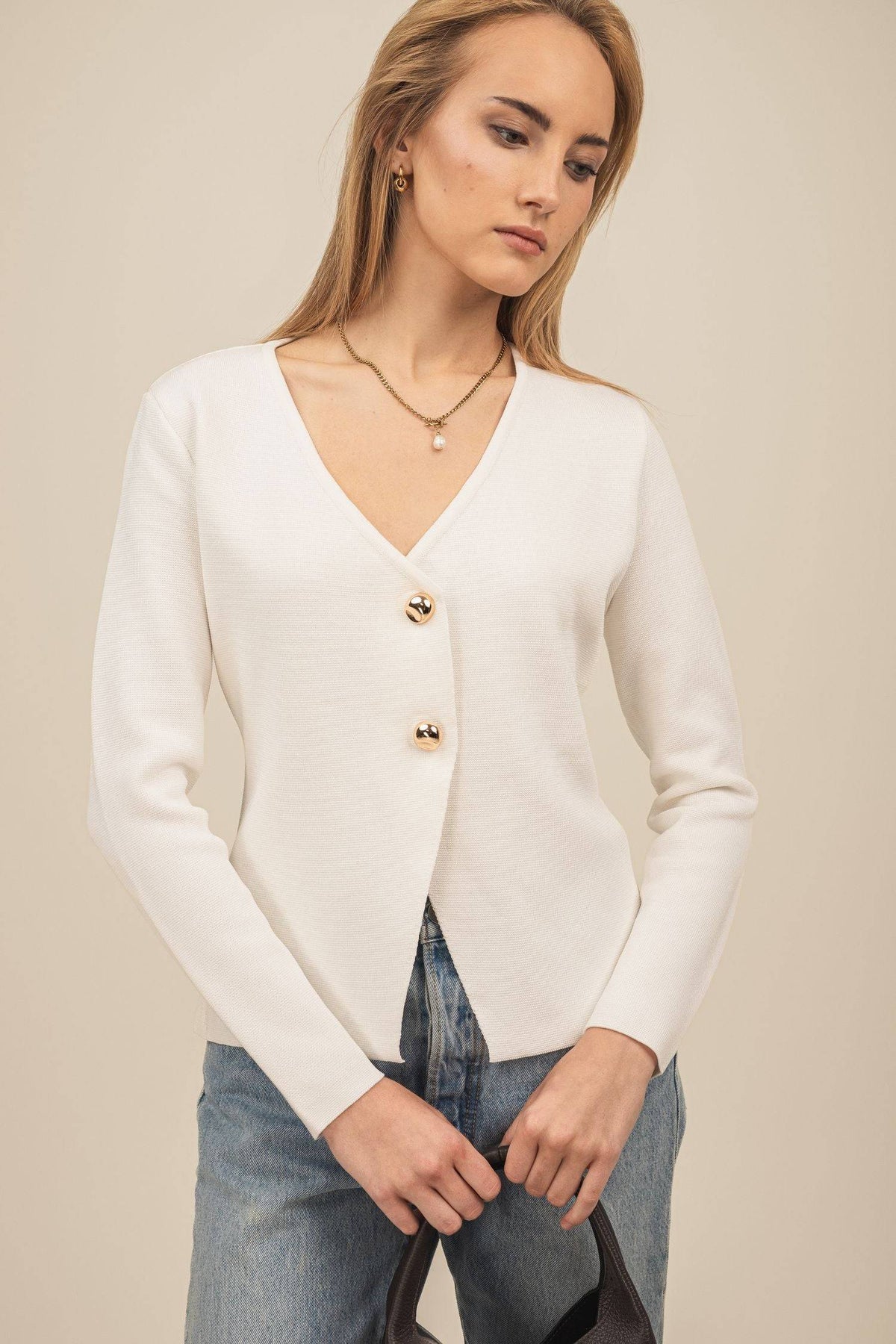 Sweter Amara – elegancki kardigan damski w kolorze białym wystylizowany z jasnymi jeansami